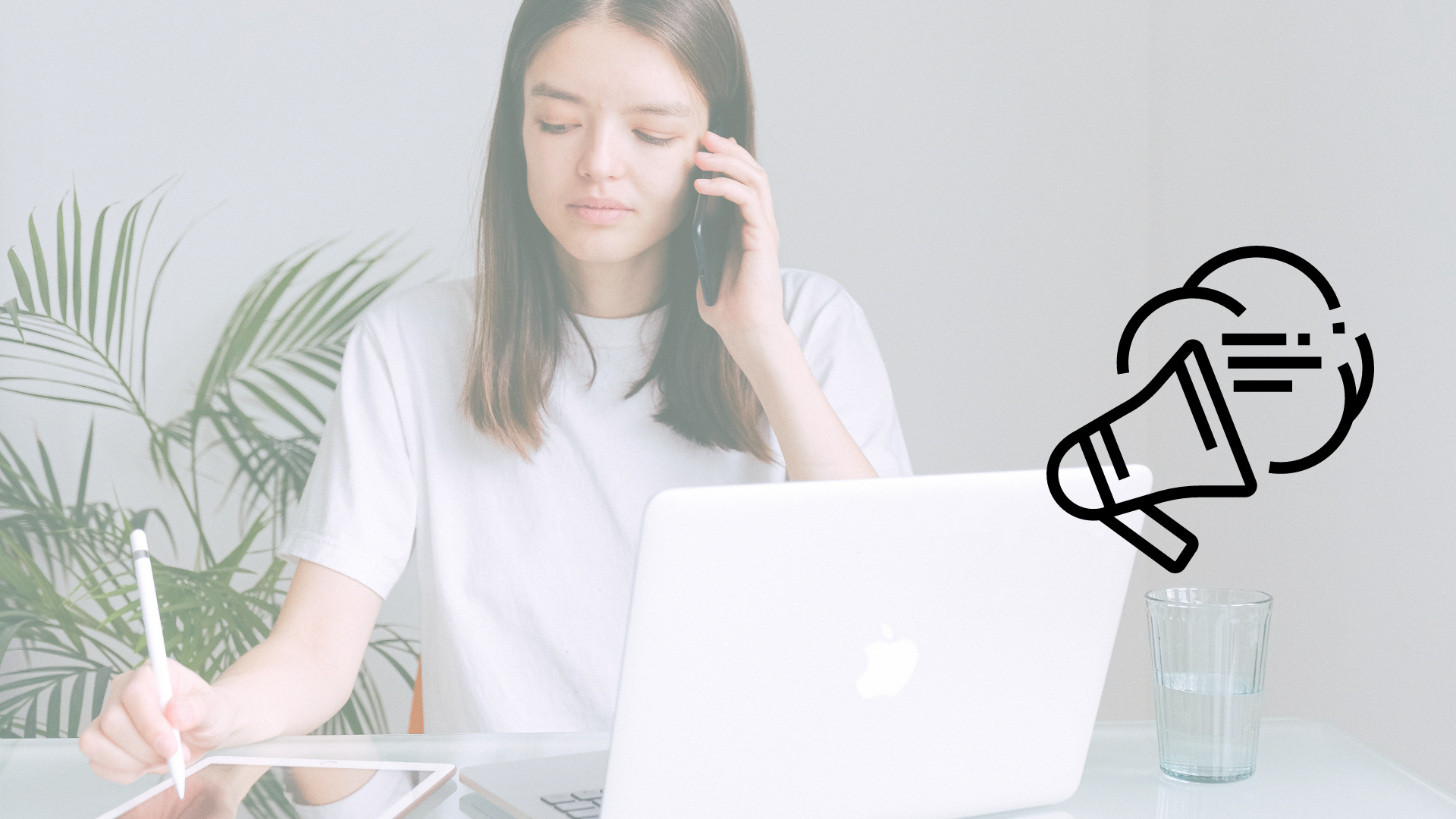 Mujer caucasica en oficina minimalista hablando por celular frente a laptop usando tablet