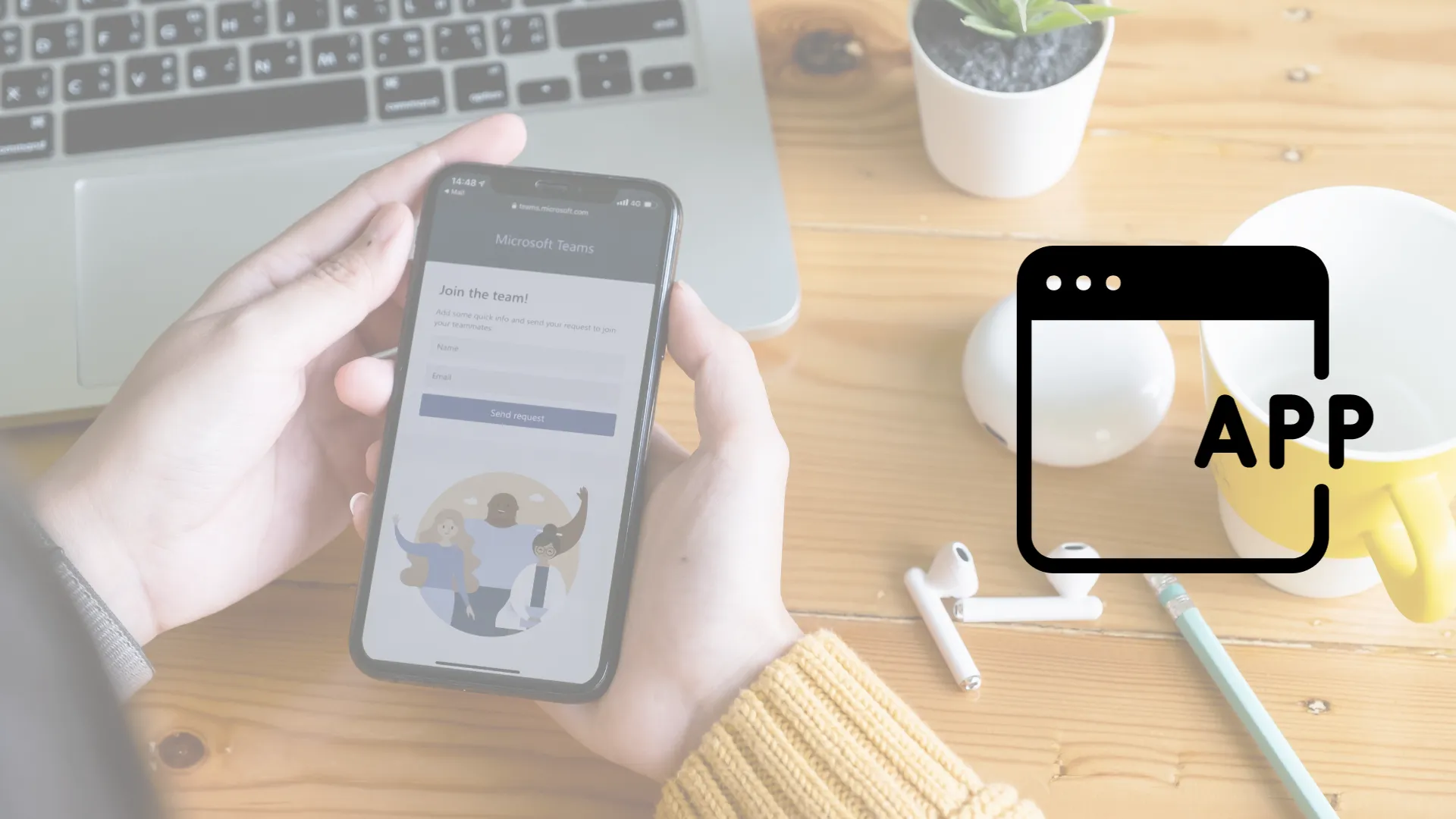 Hombre sosteniendo smarptone con la app de Teams en la pantalla, en escritorio de madera con laptop