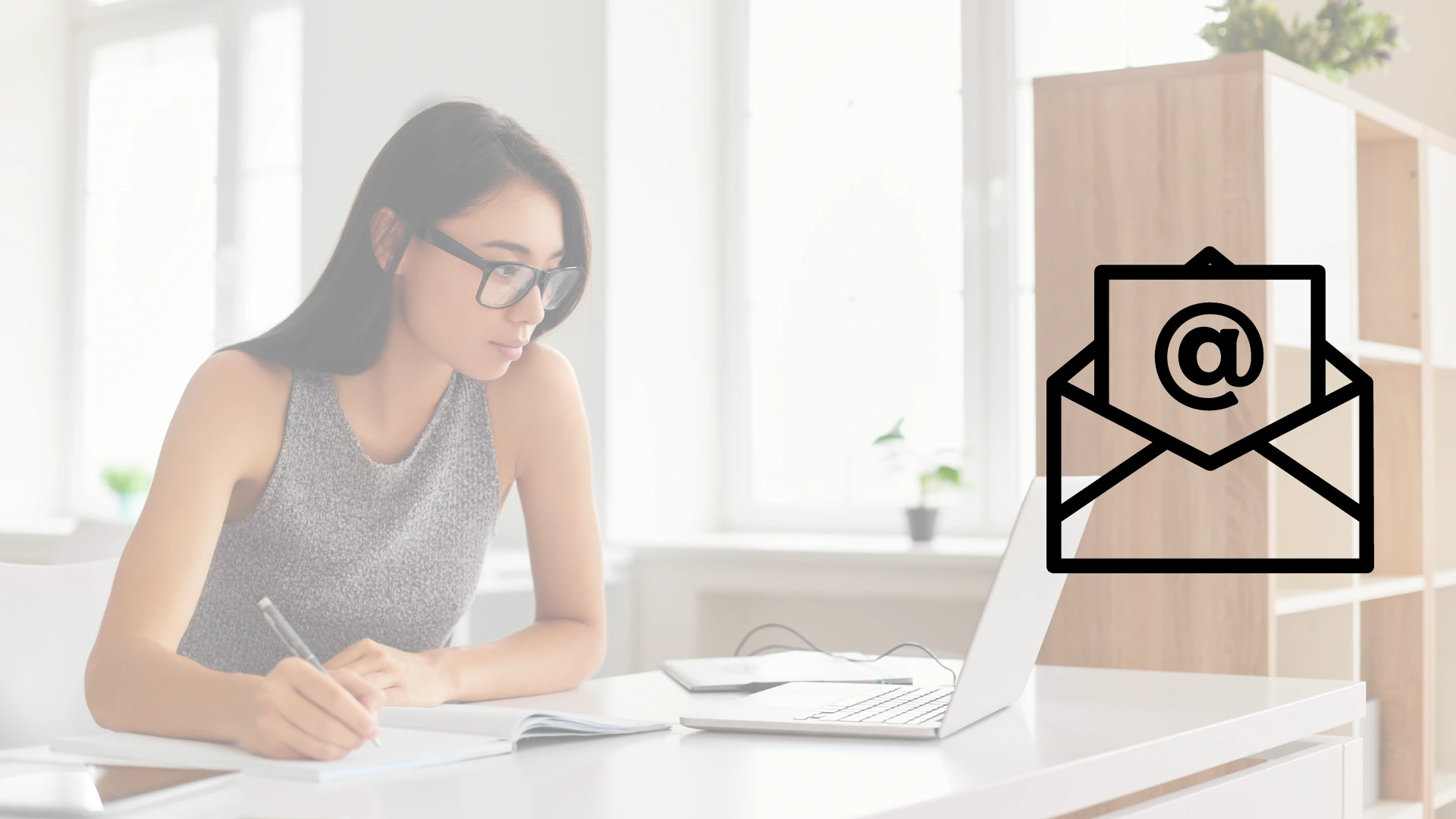 Mujer asiatica trabajando en escritorio escribiendo y viendo hacia una laptop